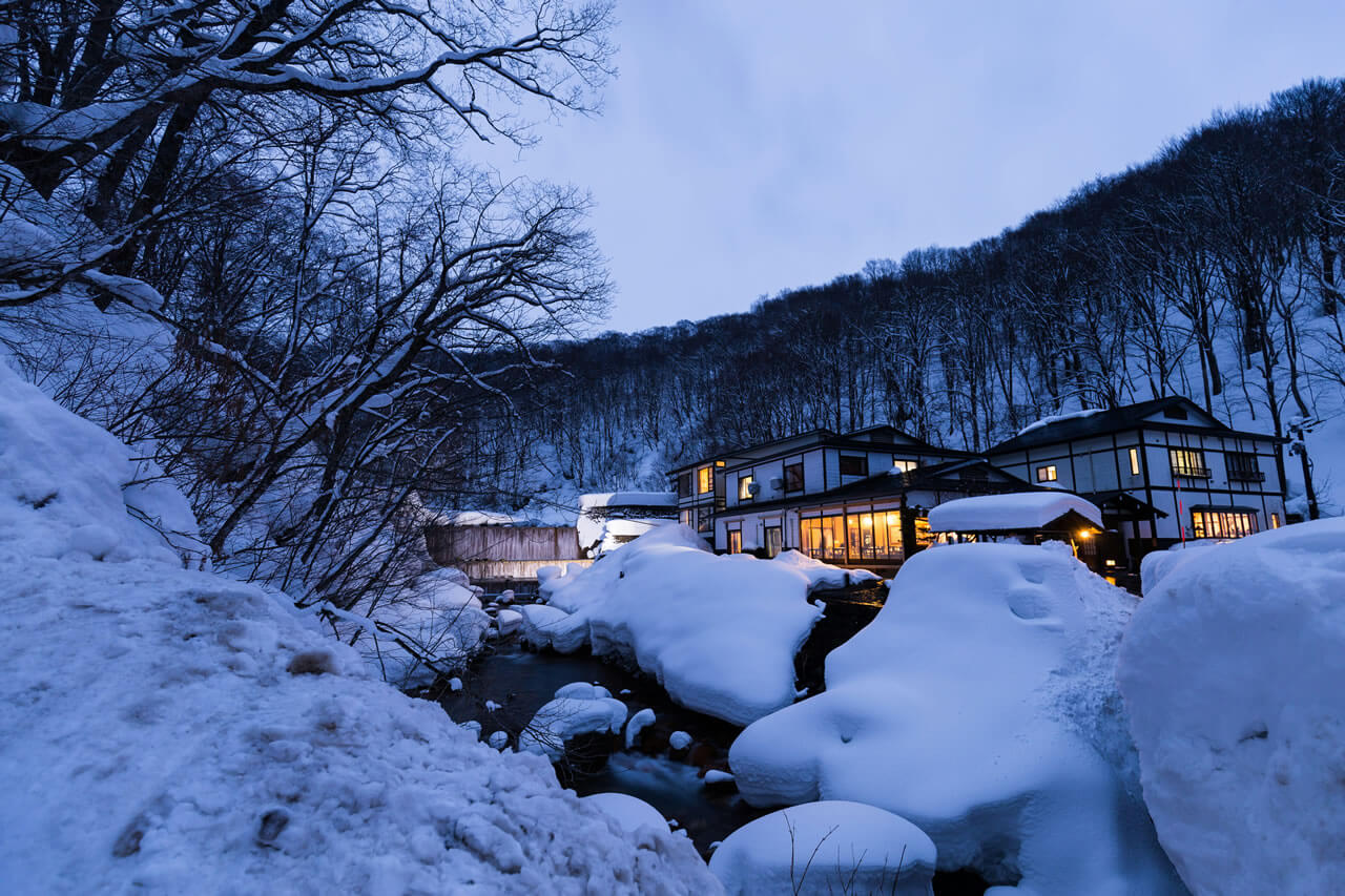 Zao Onsen village at night, traditional ryokan and river embraced by deep snow